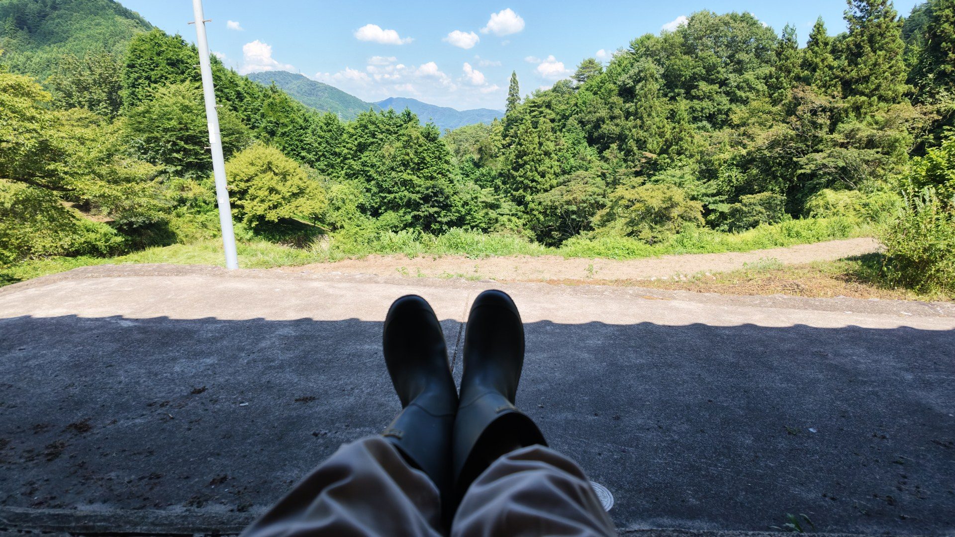 長靴を履いた足元越しに見る山々と緑